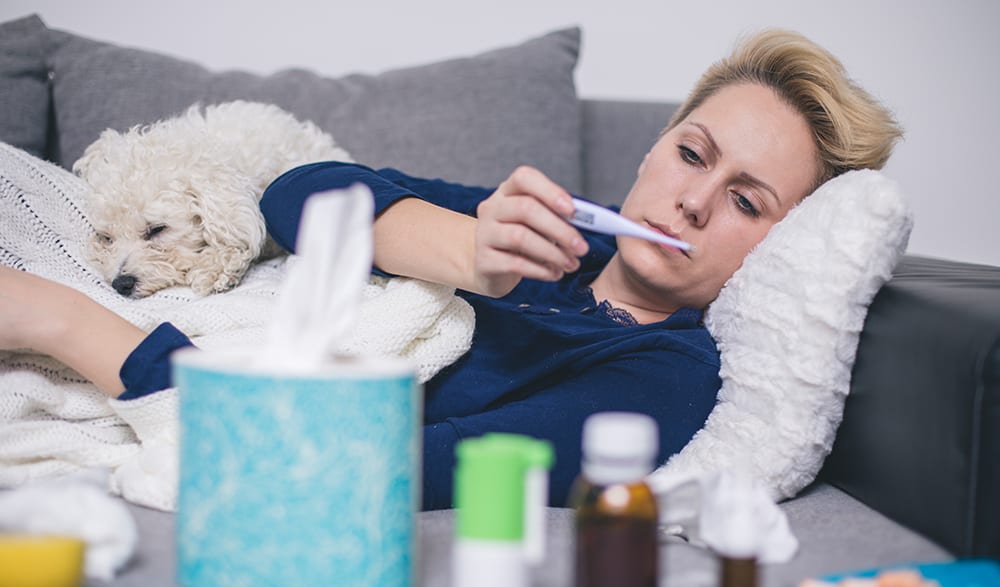 Woman checking thermometer to see if she has a fever Woman checking thermometer to see if she has a fever